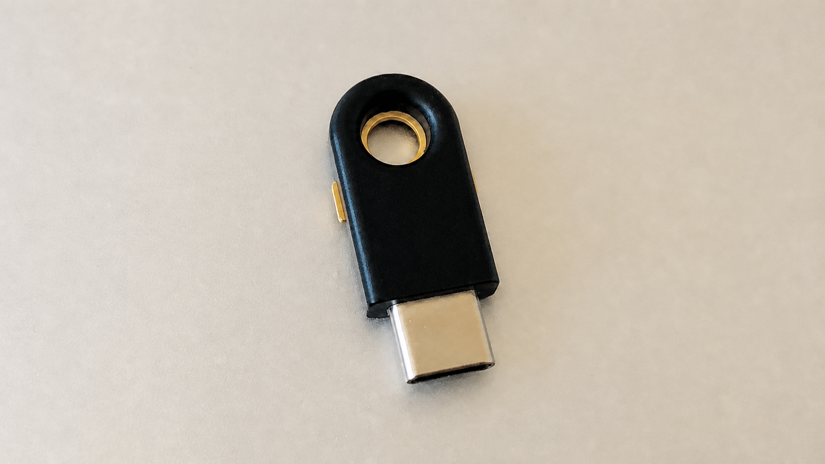 Unbranded black USB-C hardware security key on a light tabletop.