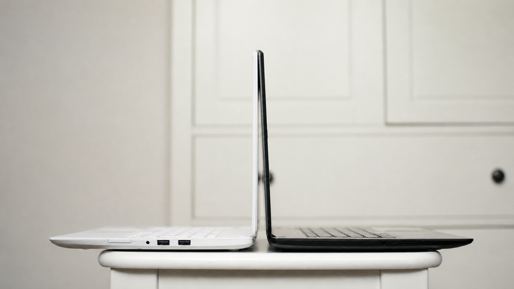 White and black laptops positioned back-to-back in profile.