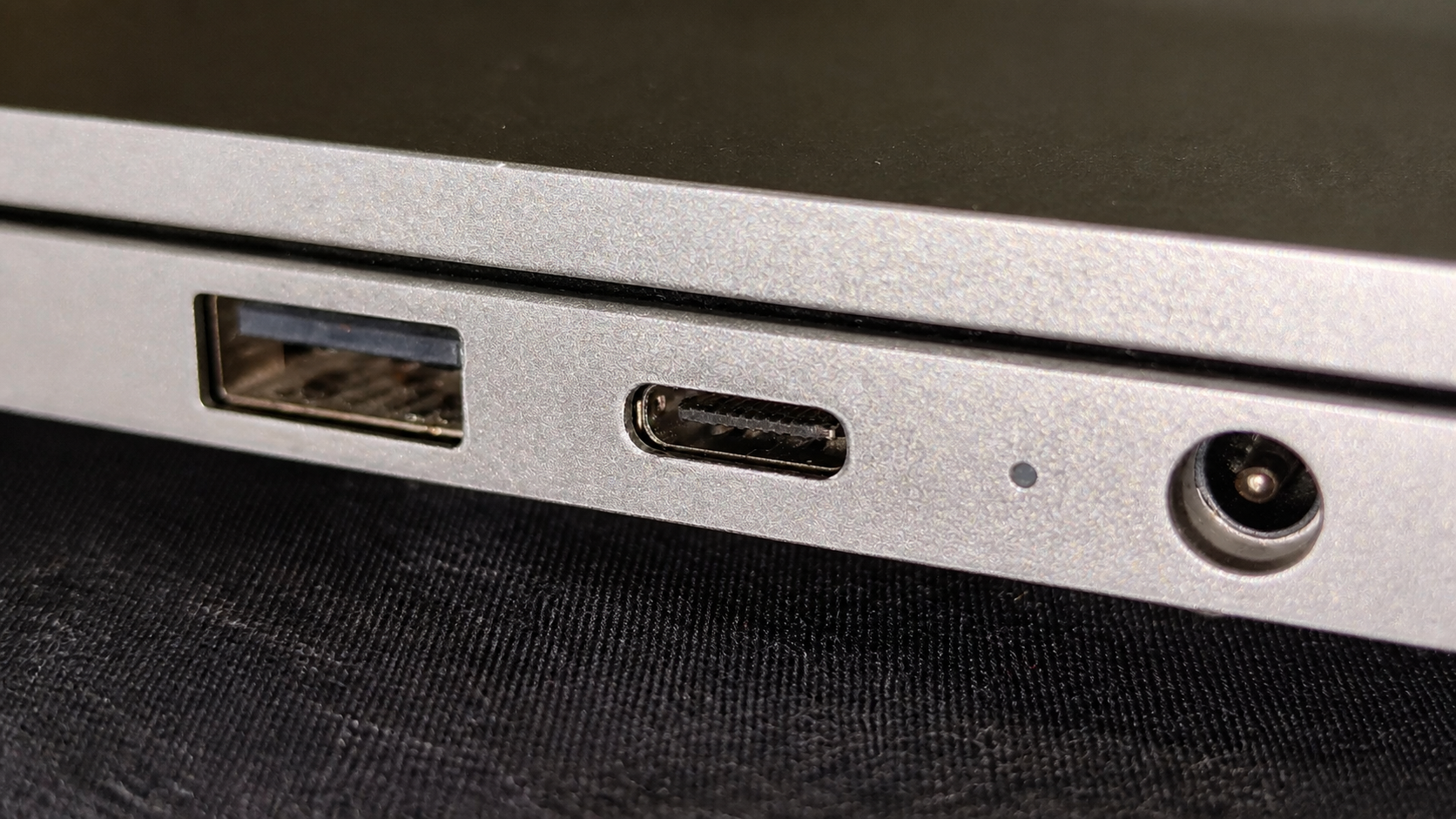 Close-up of a USB-C port between adjacent laptop power and data connectors.