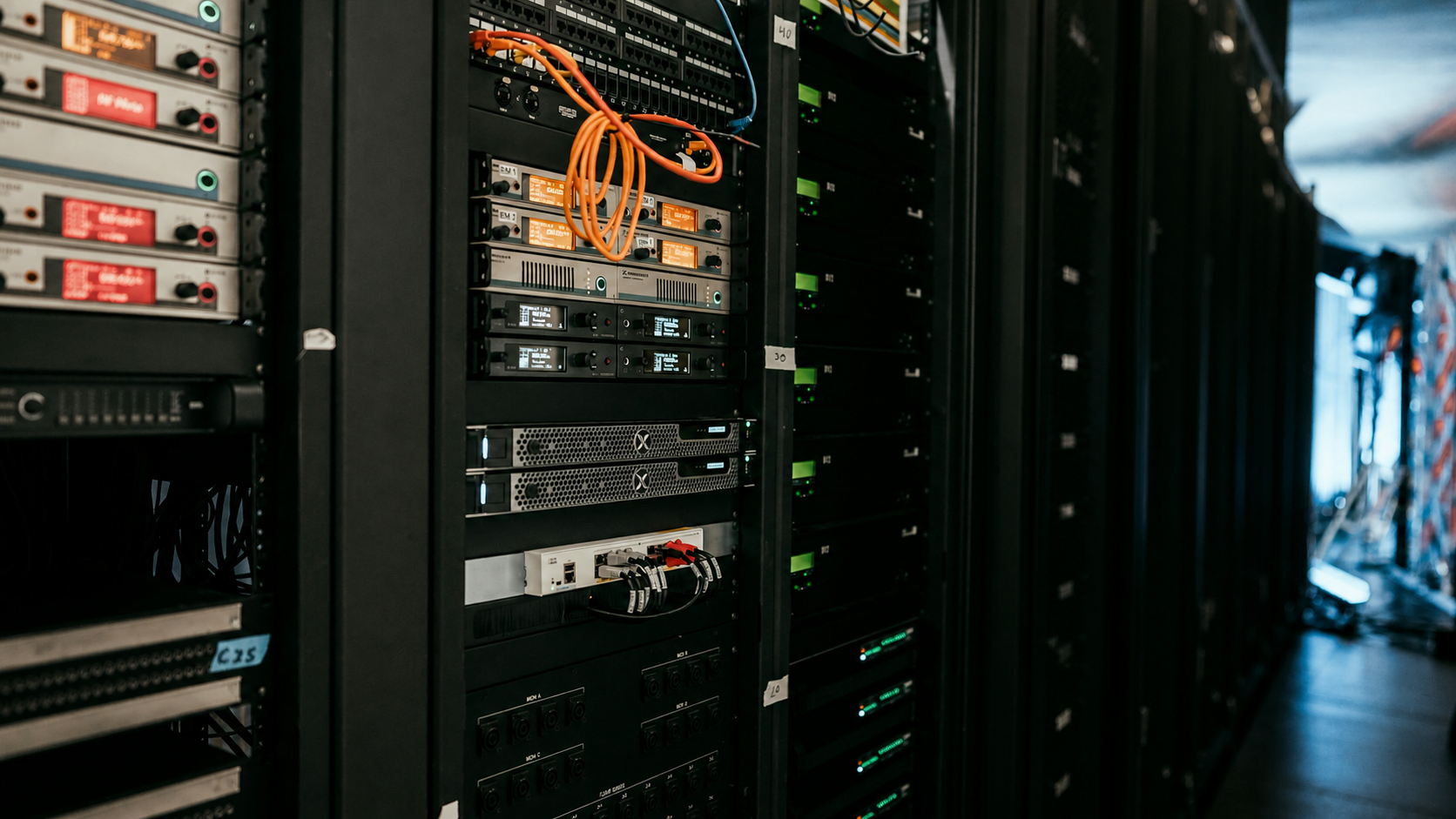 Three-quarter view of installed rack equipment, rails, cabling, and aisle clearance.